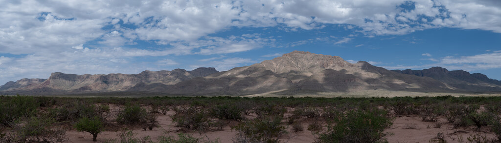 Panoramic mountain range beneath broken clouds