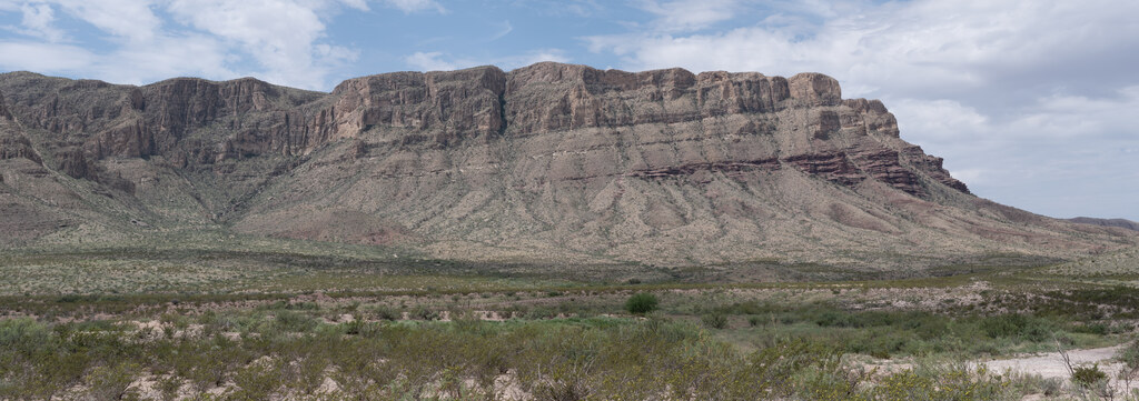 Sheer mountain escarpment above desert grassland