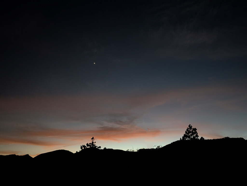 Faint twilight beneath storm clouds and mountain silhouettes