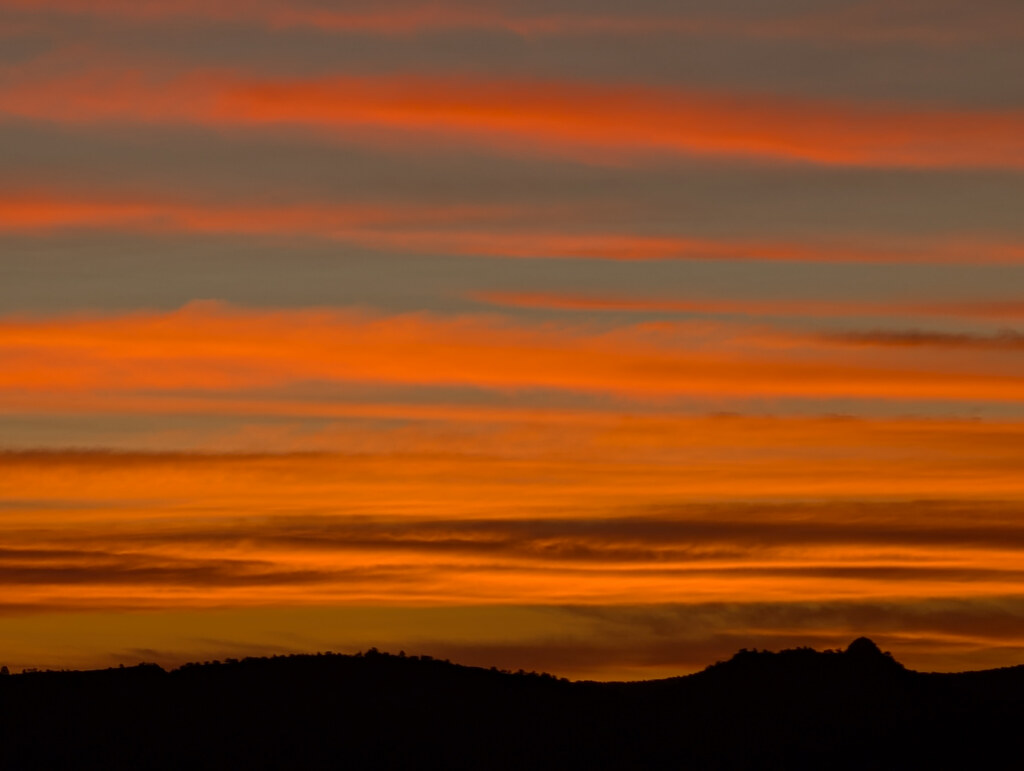 Bands of orange cloud above a mountain silhouette