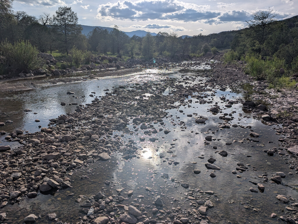 Shallow mountain creek reflecting cloud-filtered sunlight
