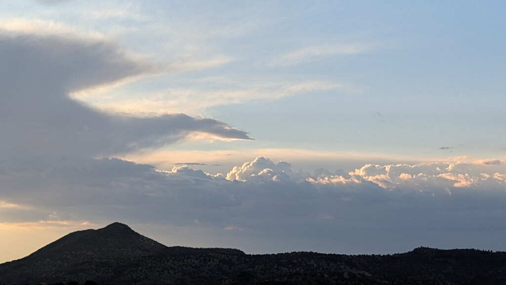 Evening clouds building behind a dark mountain peak