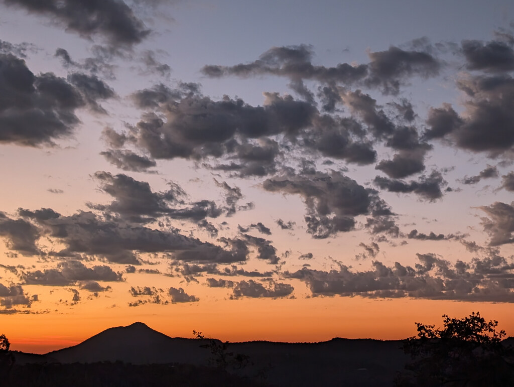 Scattered sunset clouds above a dark mountain peak