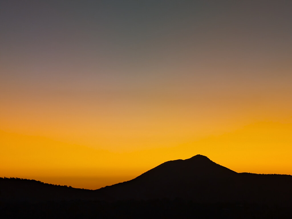 Mountain silhouette against a bright orange sunset