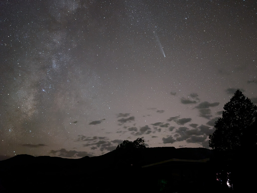 Milky Way and meteor above a dark mountain horizon
