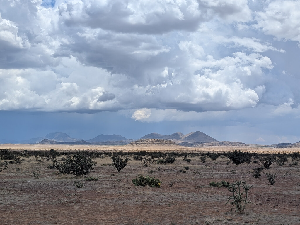 Low volcanic hills beneath towering storm clouds