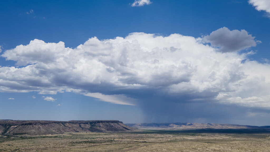 Towering white storm clouds and distant rain over the desert
