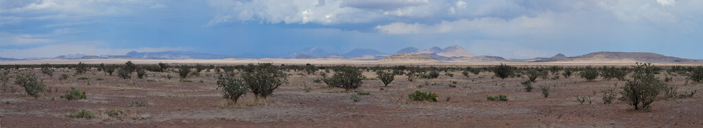 Wide desert plain and distant rain beneath layered clouds