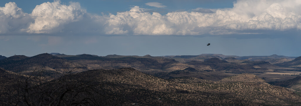 Sunlit and shadowed desert ridges beneath distant storms