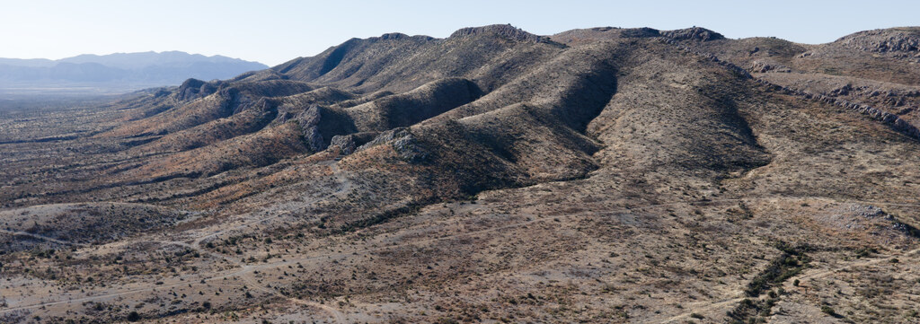 Dark rounded ridge patterned by desert drainage