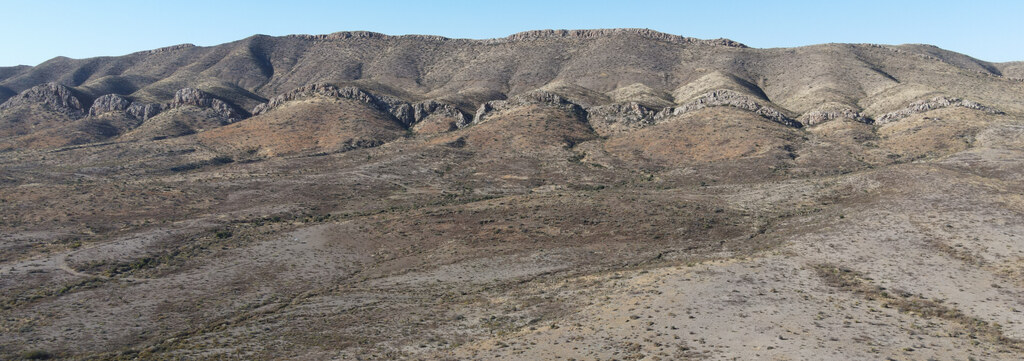 Eroded desert hills beneath a distant mountain horizon