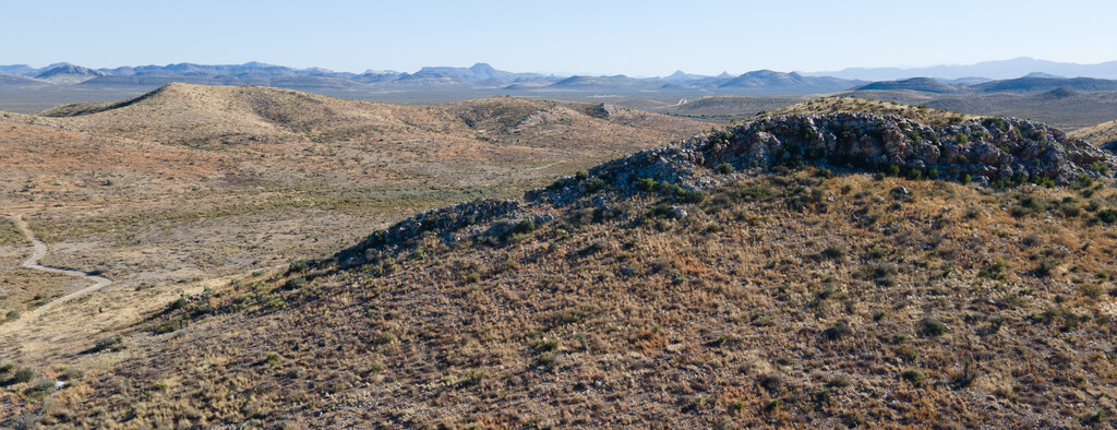 Dark rocky hill rising from the desert near Marathon