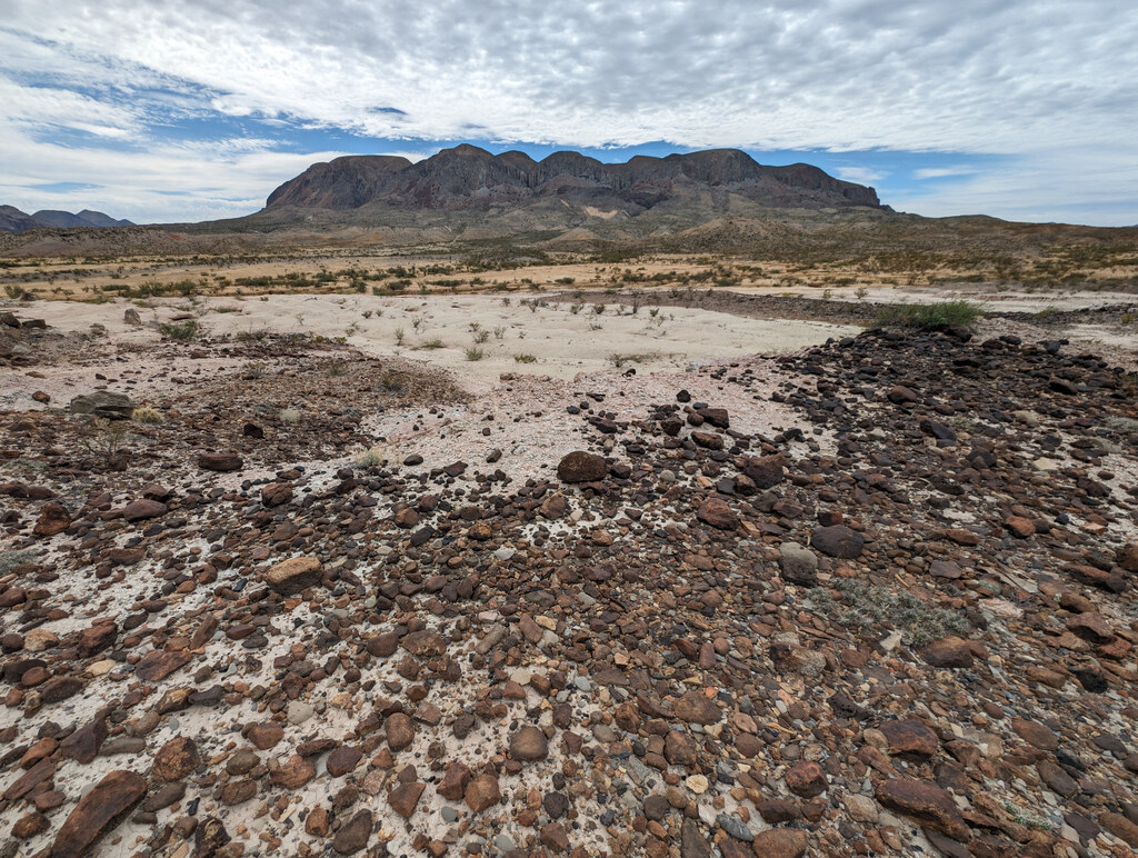 Dark mountain ridge beyond a gravel wash