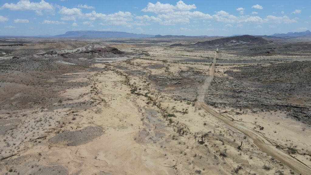 Aerial view of pale desert badlands and a winding road