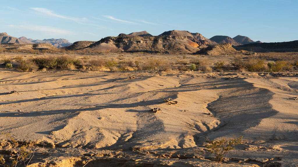 Wind-shaped sand patterns leading toward desert hills